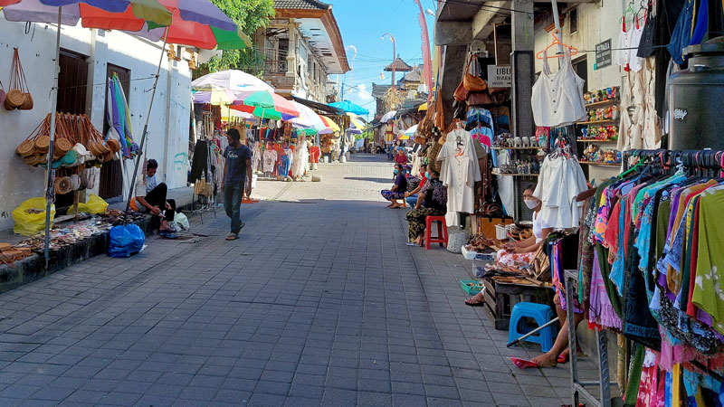 Sunny day at a vibrant street market in Bali with local vendors and colorful merchandise