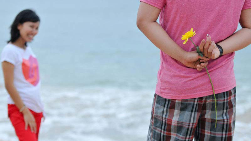 Surprise proposal with a flower on a Bali beach, capturing a candid pre-wedding moment