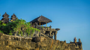 Historic sea temple in Bali perched on a rocky cliff under a clear blue sky.