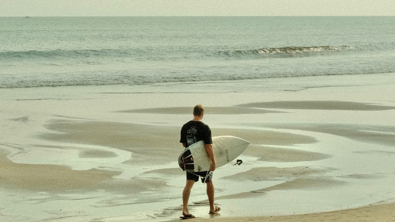 Surfer contemplating the waves at Seminyak Beach in Bali