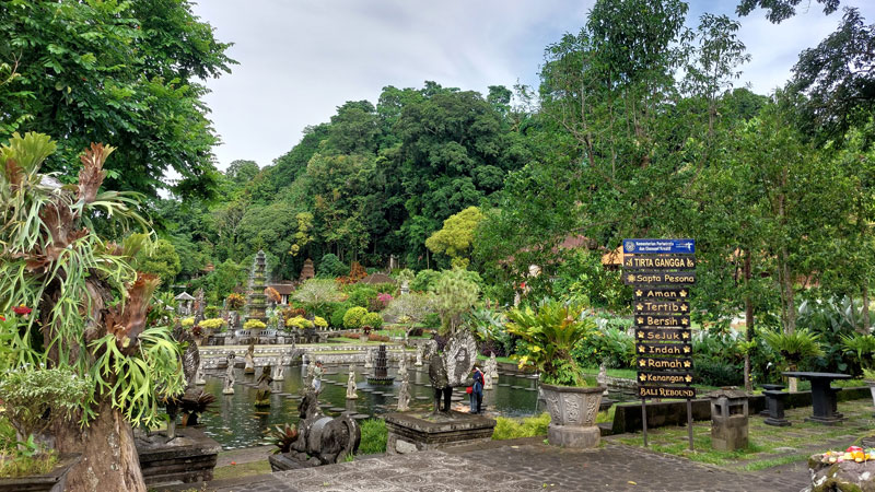 Lush gardens and ornate sculptures at Tirta Gangga Water Palace, reflecting the fusion of Balinese and Chinese architecture amidst Bali's natural landscape.