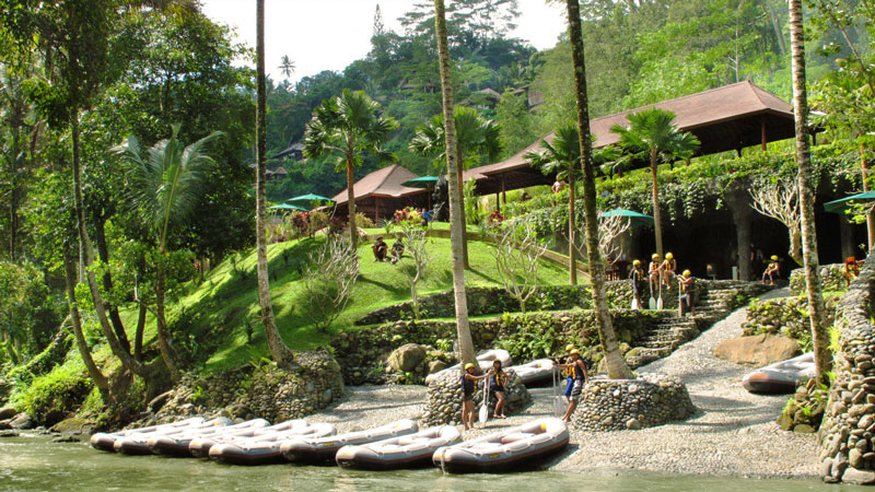 Rafting gear lined up along the Ayung River bank in Ubud, with adventurers preparing for their river kayaking experience.