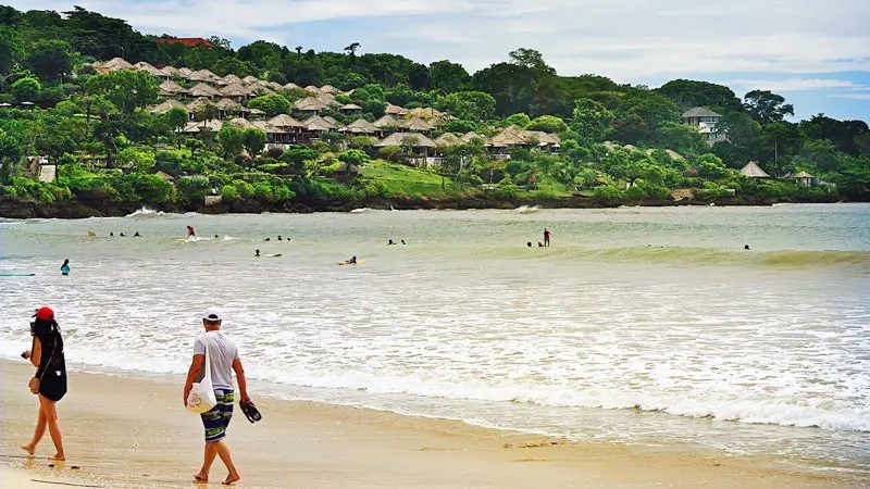 Tourists take a walk on the edge of Jimbaran Beach in the afternoon.