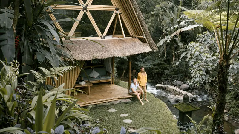 Bamboo cabin near a river in Bali surrounded by tropical greenery, ideal for budget-friendly honeymoon accommodation.