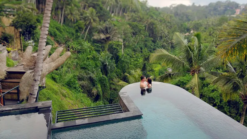 Couple relaxing in an infinity pool surrounded by lush greenery in Ubud.