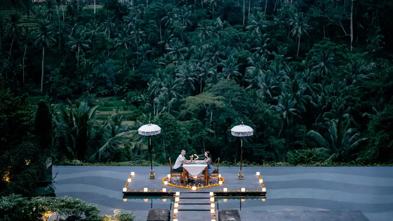 Couple enjoying a romantic candlelit dinner in Bali with a jungle view.