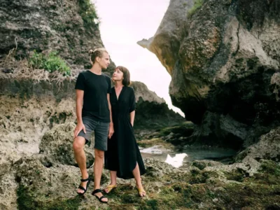 A couple enjoying a romantic moment by the rocky cliffs of a serene Bali beach.