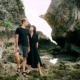 A couple enjoying a romantic moment by the rocky cliffs of a serene Bali beach.