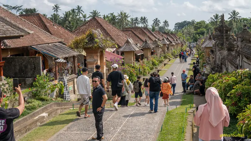 Main street of Penglipuran Village Bali, filled with visitors enjoying the car-free environment and traditional Balinese homes.