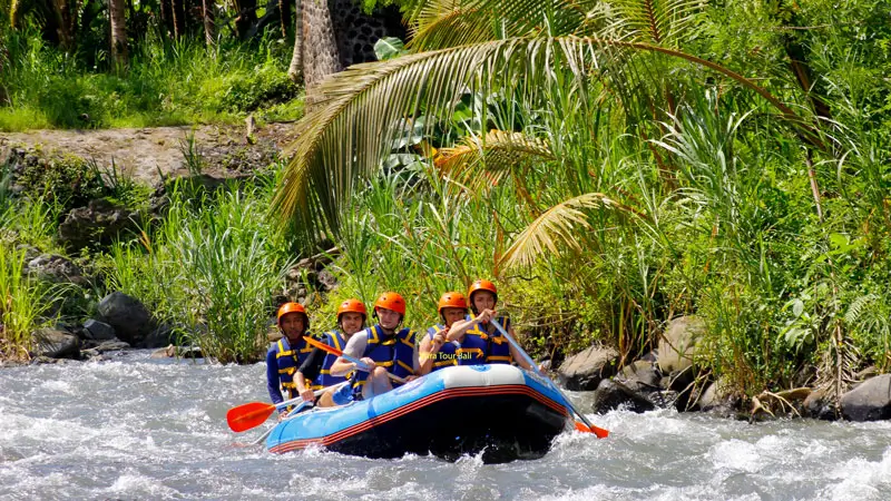 Group of tourists enjoying a scenic rafting adventure on Telaga Waja River in Bali with Avatar Rafting, wearing safety gear.